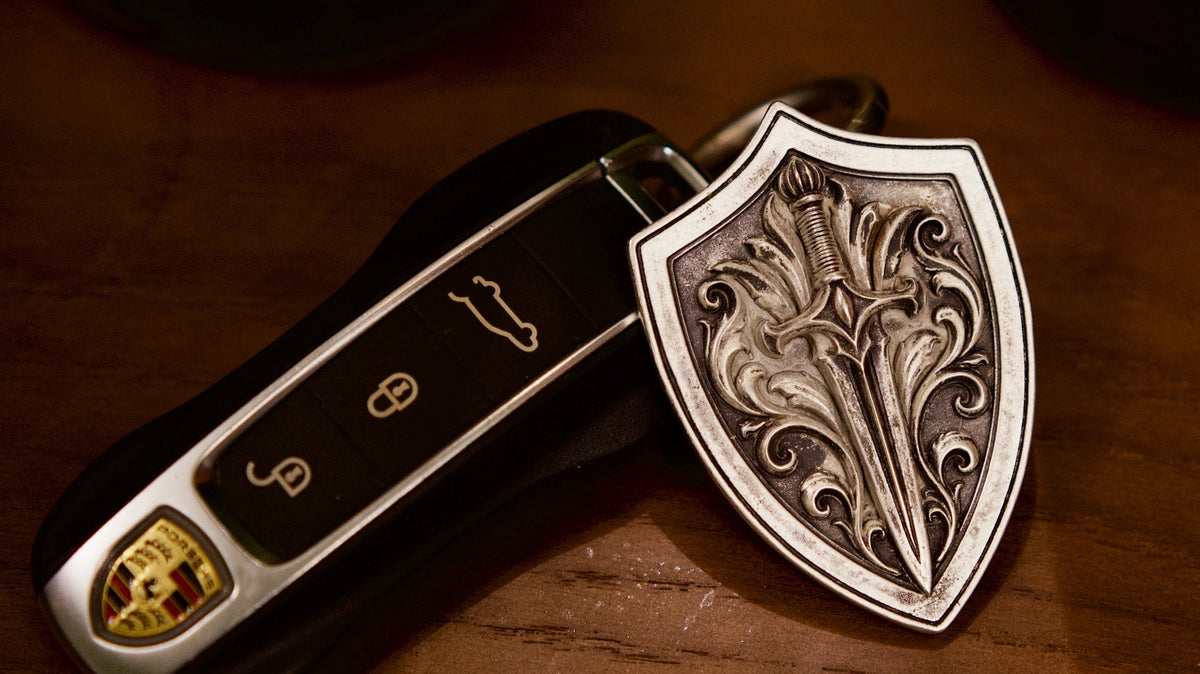 Aegis Blade Shield Silver Keychain, front view beside a car key