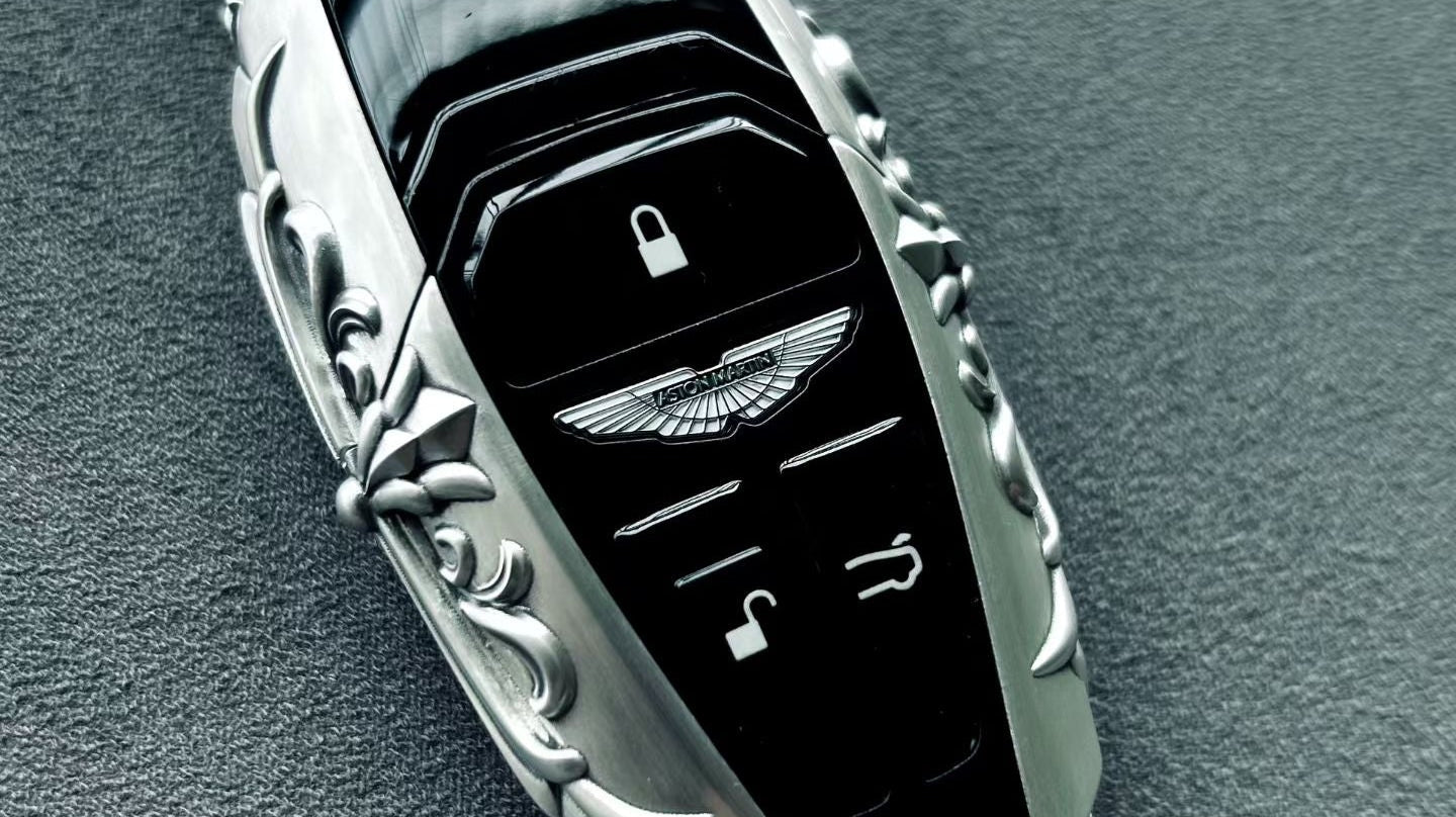 Front view of a custom sterling silver key case with button cutouts, compact shell geometry, and refined scrollwork detail