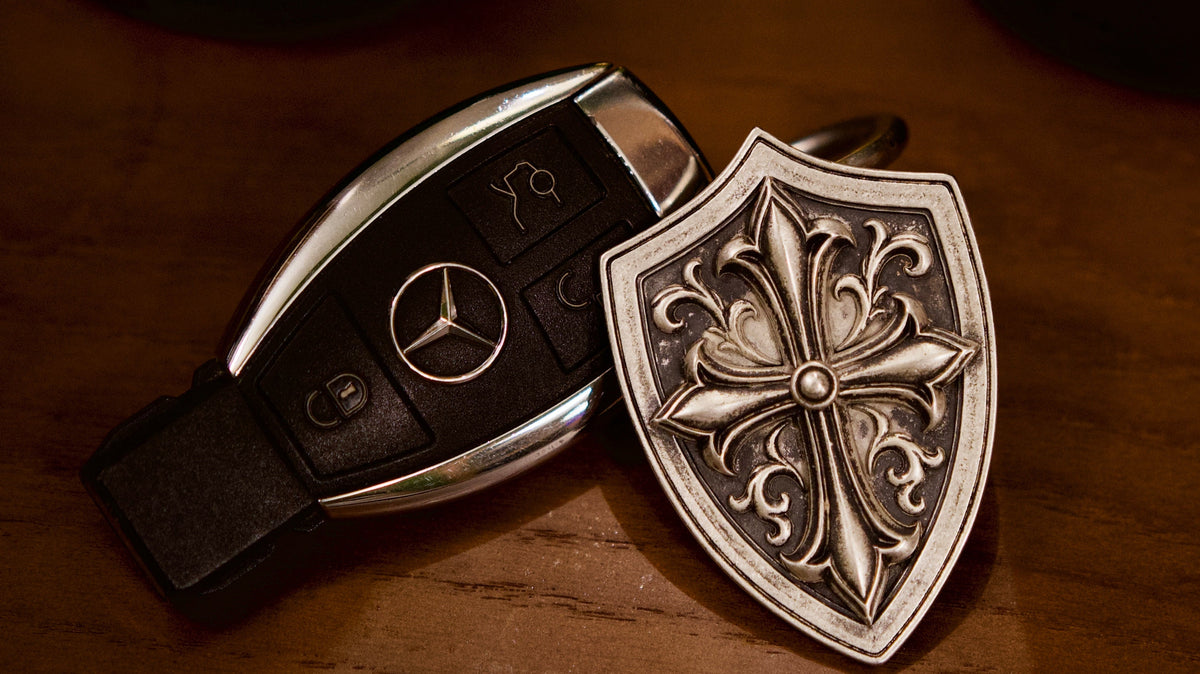 Fleur de Croix Shield Silver Keychain, front view beside a car key