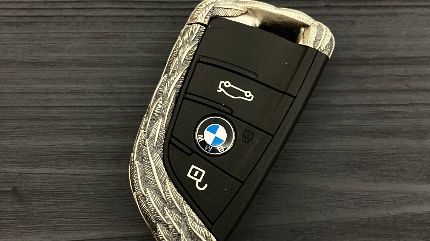 BMW key case top-angle view showing a compact pocket profile, rounded shoulders, and controlled balance in the hand