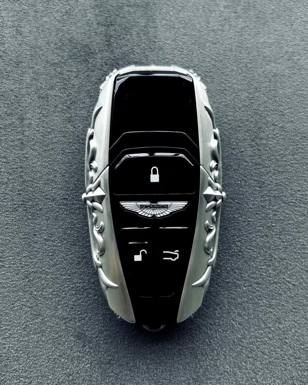 Aston Martin handcrafted sterling silver key case with key fully embedded, top-down perspective showing seamless integration and uniform engraving around solid silver perimeter