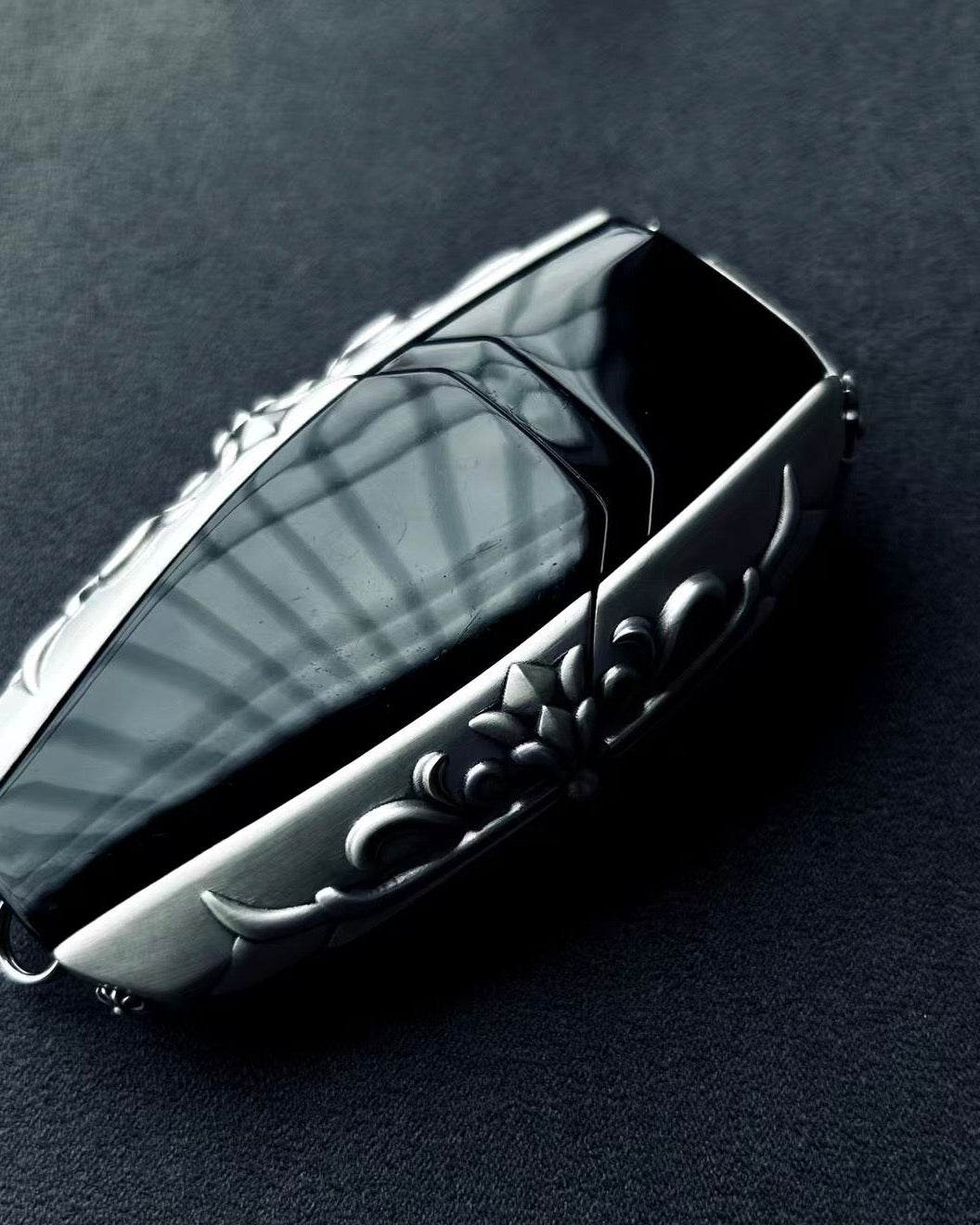 Aston Martin handcrafted sterling silver key case side 45-degree angle highlighting substantial thickness, sculpted silver edges and intentional weight (90g) with refined patina