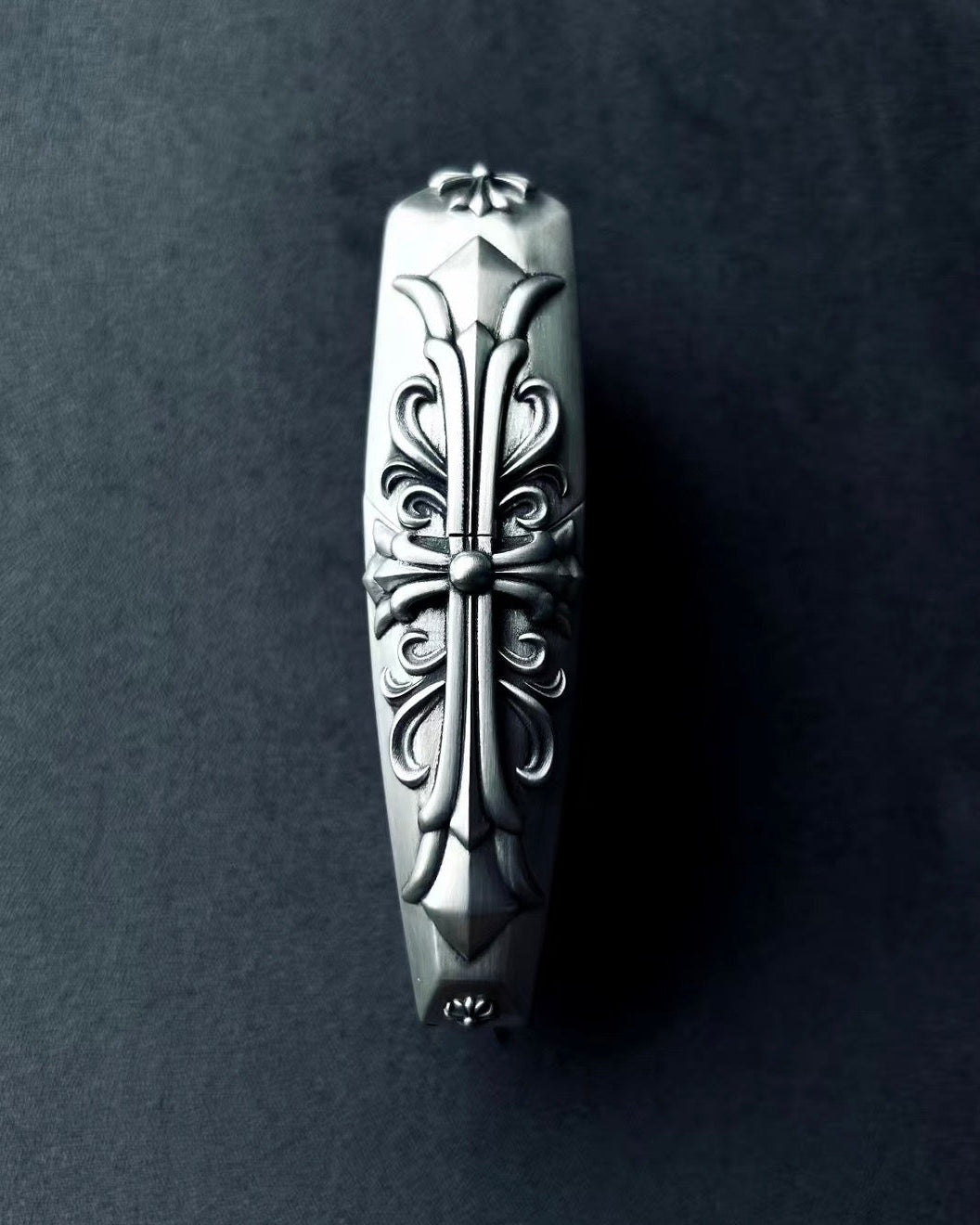 Close-up detail of Aston Martin key case side embossing showing intricate hand-engraved scrollwork patterns carved into solid 925 sterling silver with considerable presence
