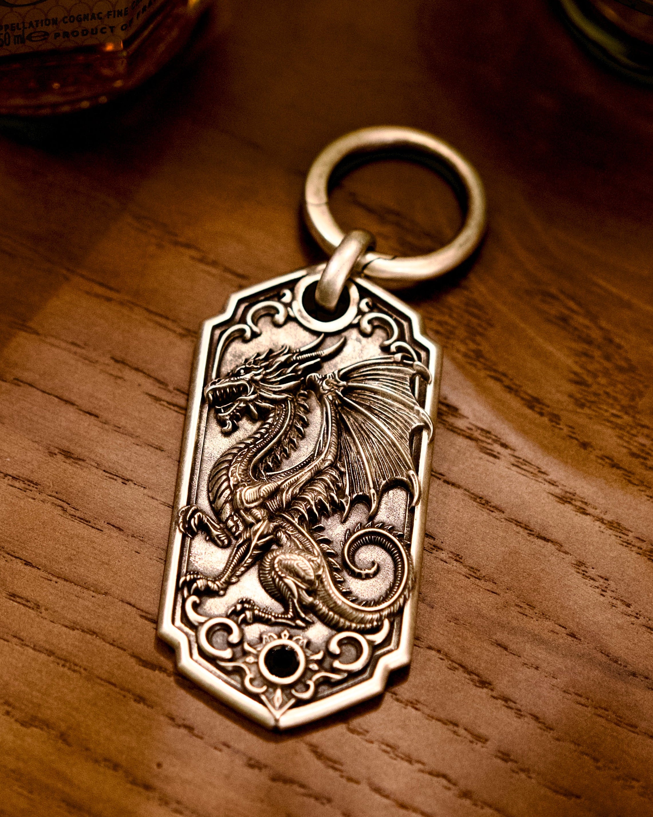 Bespoke dragon-motif key tag, front view on wooden table