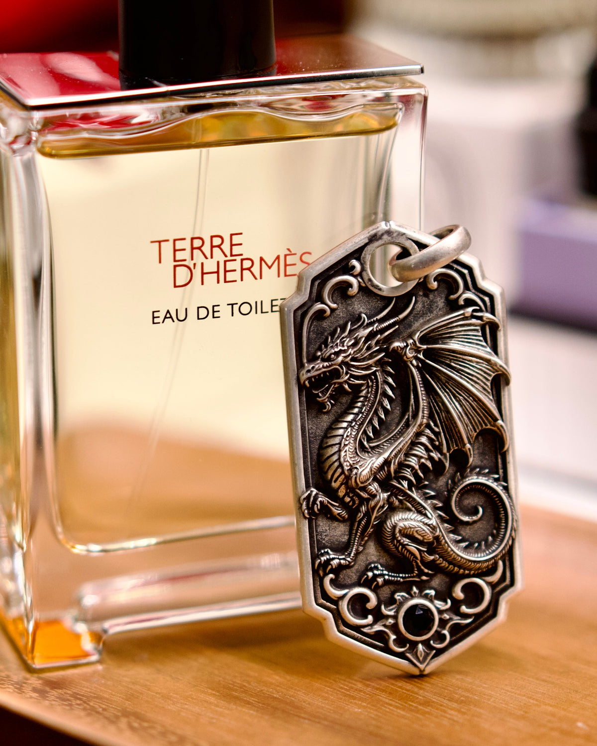 Bespoke dragon-motif key tag, lifestyle display beside fragrance bottle
