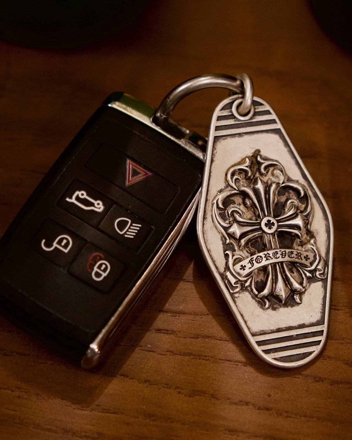 Fleur-de-Lis Crest Silver Keychain, front view beside a car key