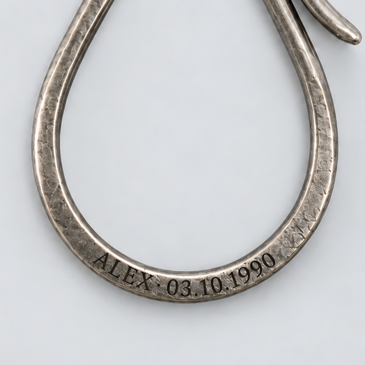 Illustrative personal engraving on the Patina Key Hook lower loop; a close-up of ALEX and a birthday, with no text overlay