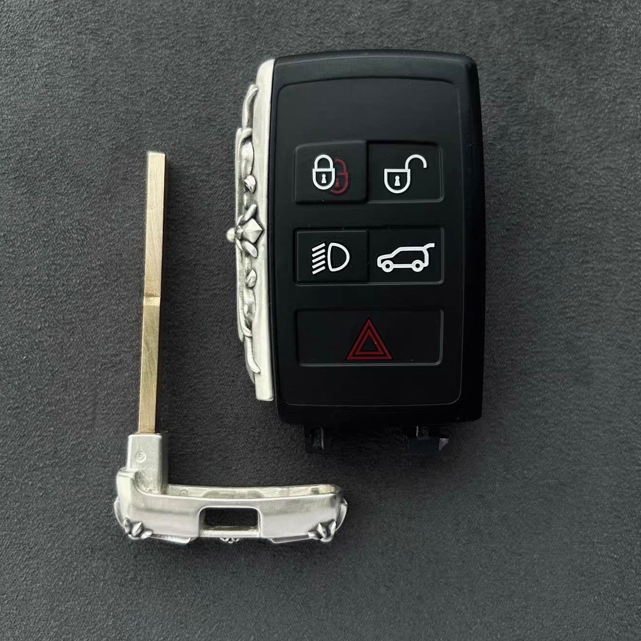 Land Rover key case installation process showing key fob separated from silver shell with metal prying tool, demonstrating easy DIY installation and removable design