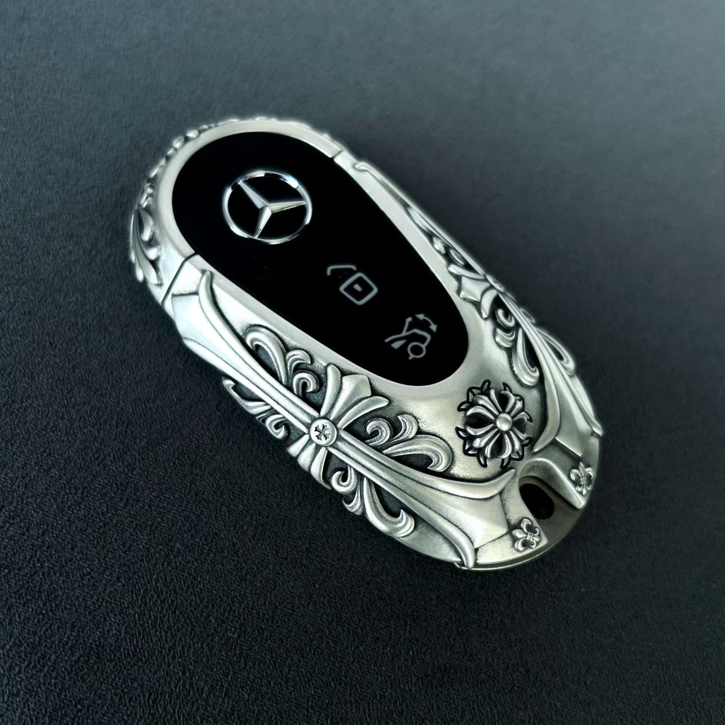 Mercedes rounded capsule key case top view showing precision button layout and symmetrical floral relief pattern craftsmanship