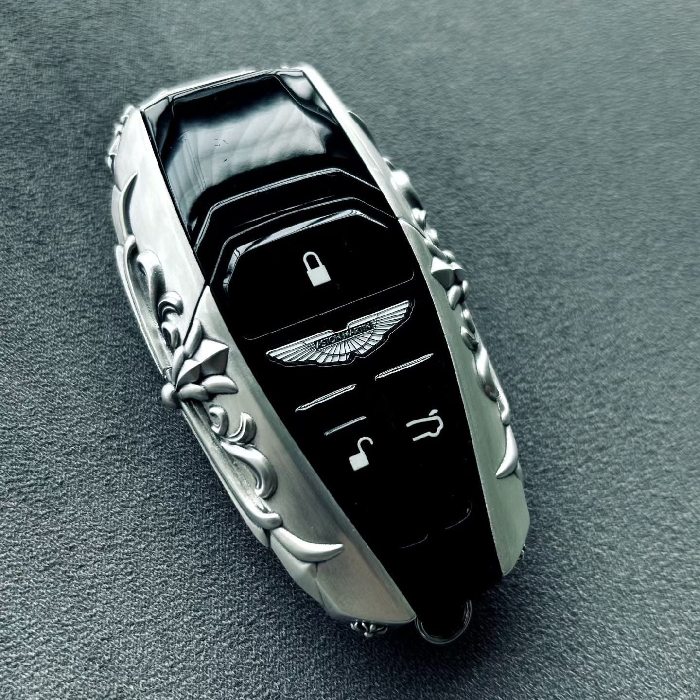 Front view of a custom sterling silver key case with button cutouts, compact shell geometry, and refined scrollwork detail