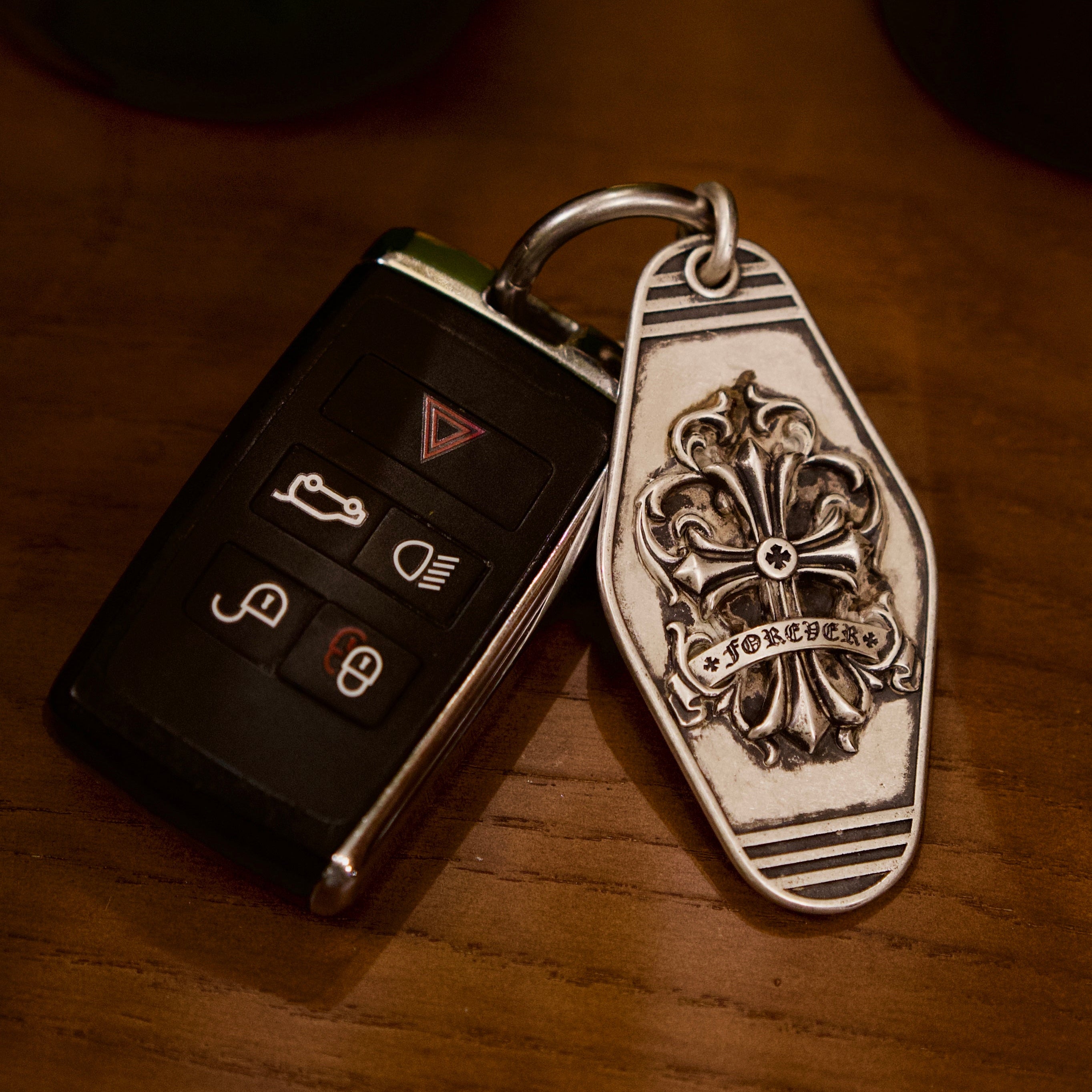Fleur-de-Lis Crest Silver Keychain, front view beside a car key