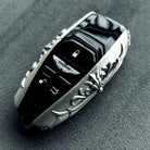 Aston Martin handcrafted sterling silver key case 45-degree angle view showing iconic winged emblem, three-button layout and ornate engraved solid silver frame with refined detailing