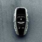 Aston Martin handcrafted sterling silver key case with key fully embedded, top-down perspective showing seamless integration and uniform engraving around solid silver perimeter