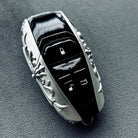 Aston Martin handcrafted sterling silver key case front view featuring iconic Aston Martin winged emblem, lock/unlock/trunk buttons and symmetrical engraved precious metal frame