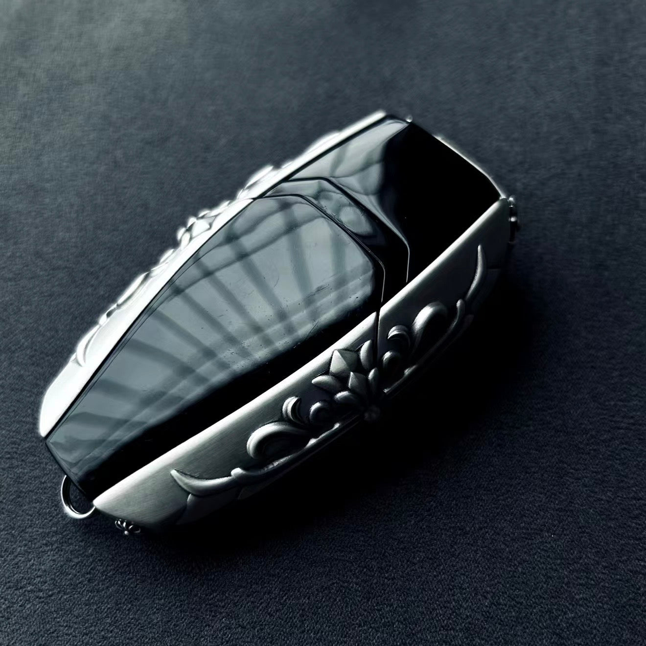 Aston Martin handcrafted sterling silver key case side 45-degree angle highlighting substantial thickness, sculpted silver edges and intentional weight (90g) with refined patina