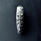 Close-up detail of Aston Martin key case side embossing showing intricate hand-engraved scrollwork patterns carved into solid 925 sterling silver with considerable presence