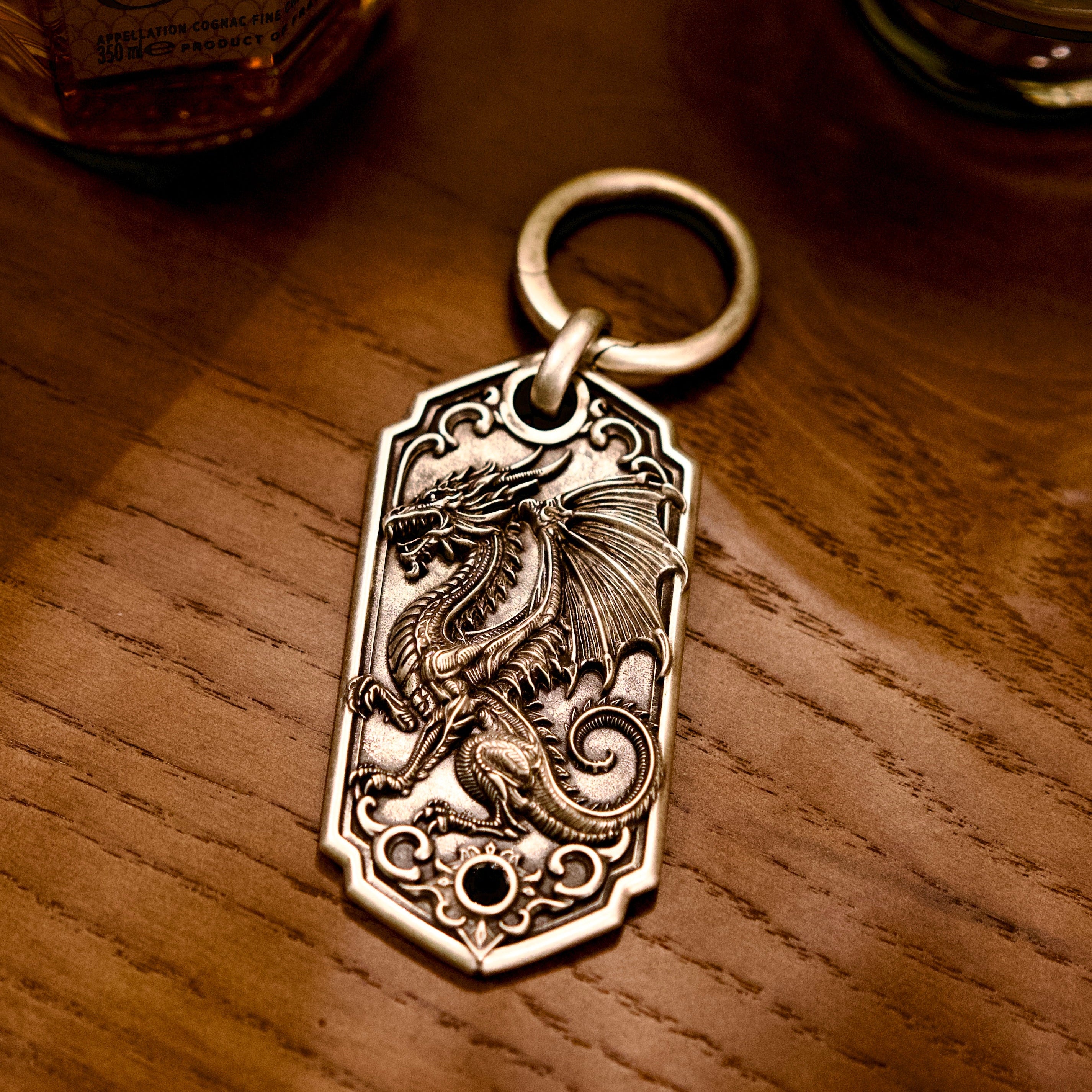 Bespoke dragon-motif key tag, front view on wooden table