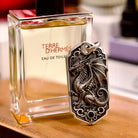 Bespoke dragon-motif key tag, lifestyle display beside fragrance bottle