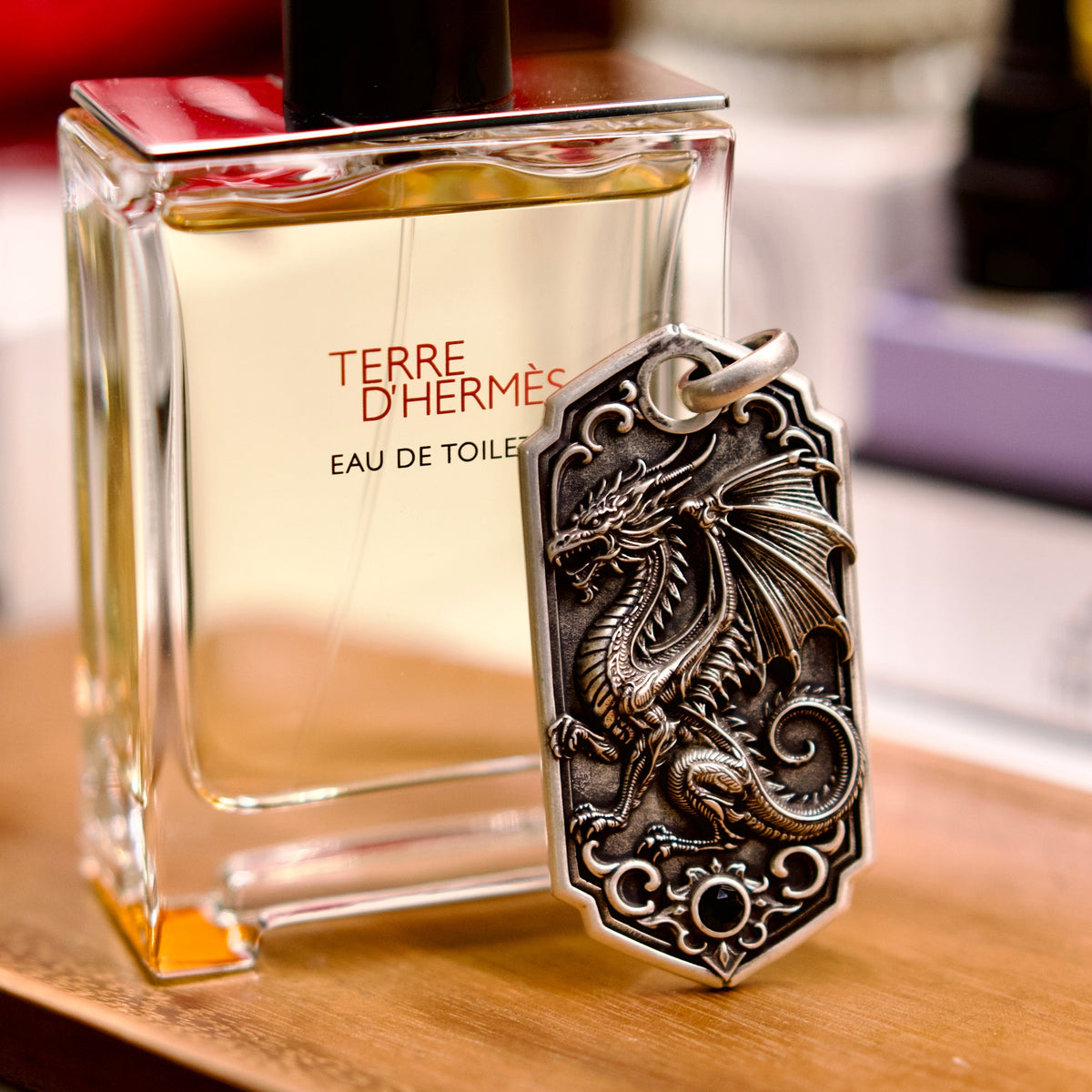 Bespoke dragon-motif key tag, lifestyle display beside fragrance bottle