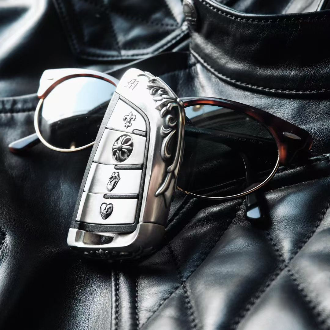 BMW slim edge key case paired with metal sunglasses on black leather background suggesting automotive interior and premium accessories coordination