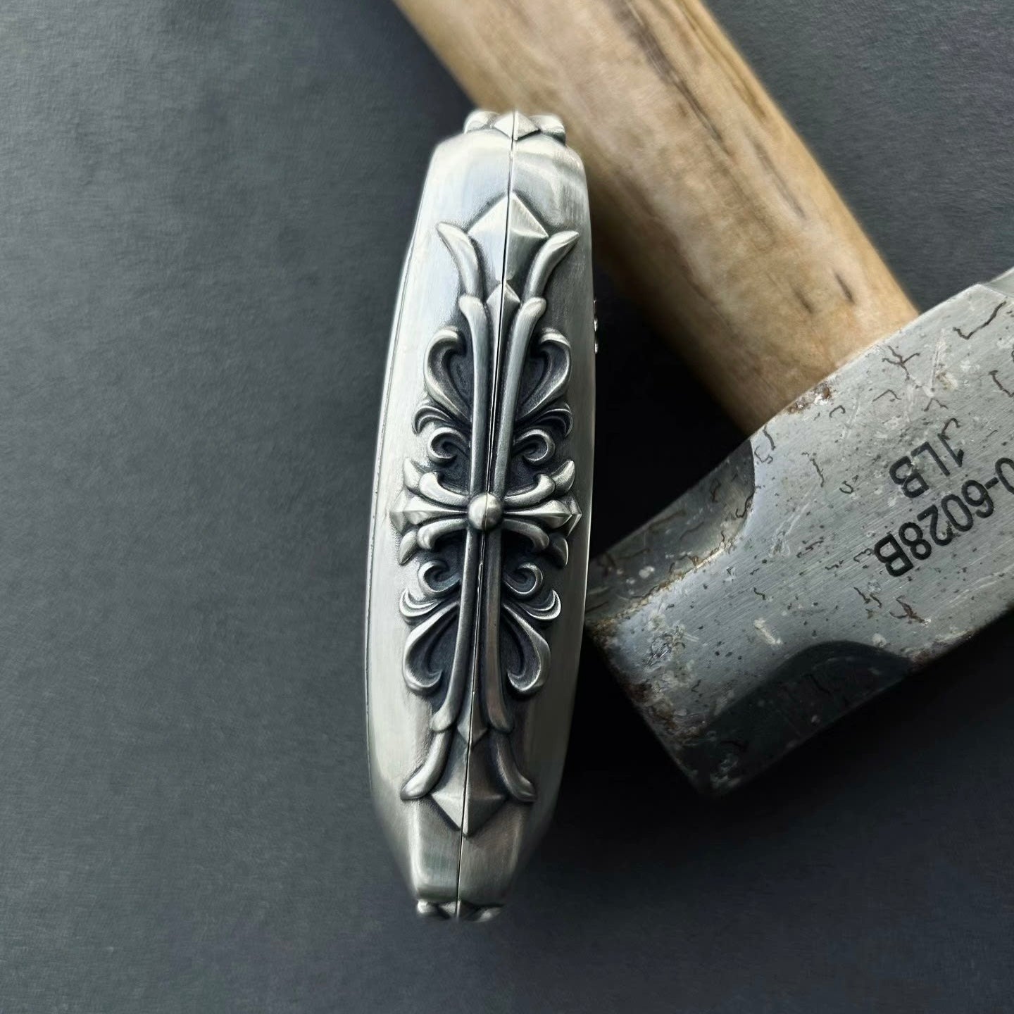 Close-up of intricate floral scrollwork engraving on sterling silver surface with red PANIC button visible