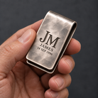 Personalized silver money clip shown in an adult hand for scale