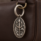 Spring-gate silver ring connecting a Poseidon MYTHOS charm to a leather bag; charm and bag not included