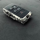 Land Rover key fitted into custom silver engraved case showing full functionality with 5-button layout (lock, unlock, trunk, hazard, engine) and sleek design