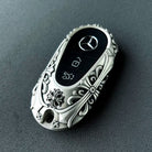 Mercedes Rounded Capsule handcrafted key case Nickel Silver front view with ornate floral relief pattern and three-pointed star emblem