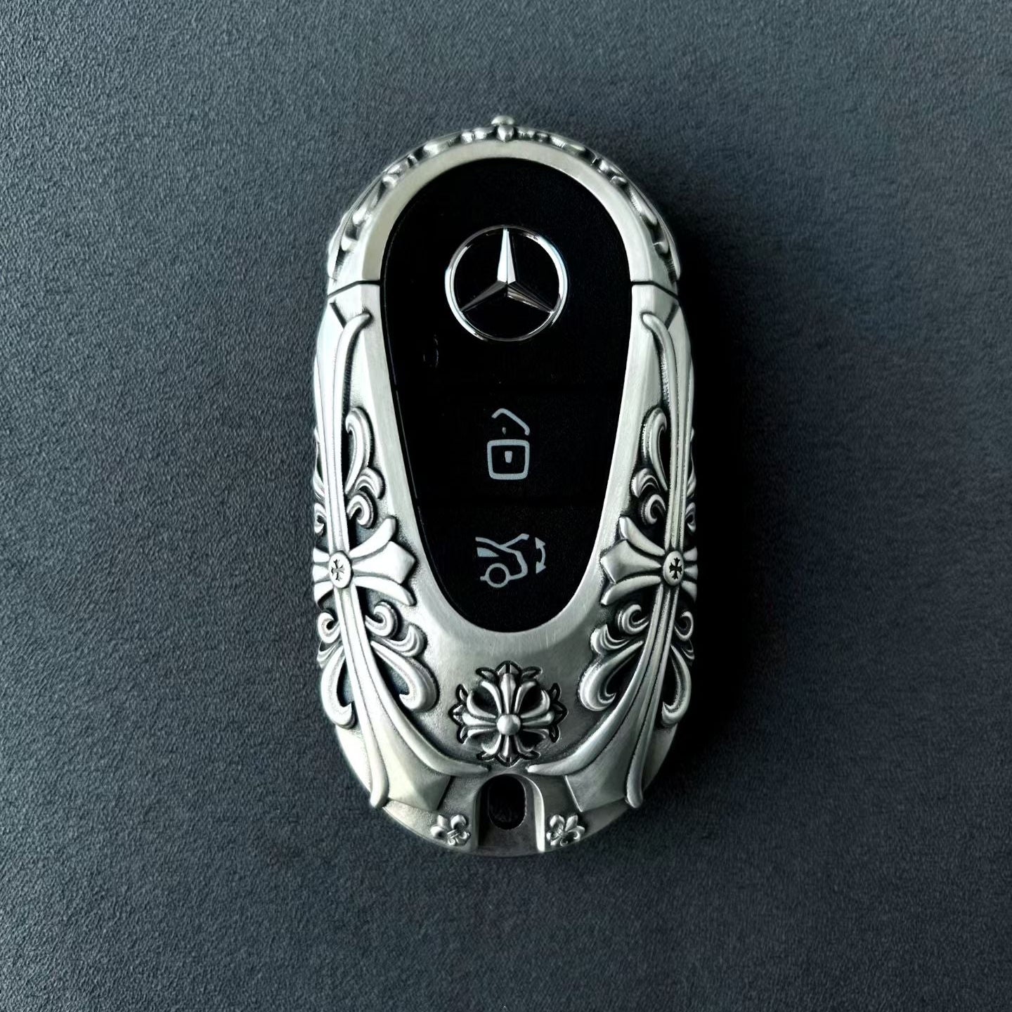 Mercedes rounded capsule key case diagonal rear angle showcasing uniform relief pattern and weighty precision from multiple perspectives