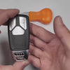 Audi handcrafted sterling silver key case installation demonstration showing precise fit for three-button key fob, seamless integration with factory key featuring iconic four-ring emblem, and straightforward installation process using included tool.