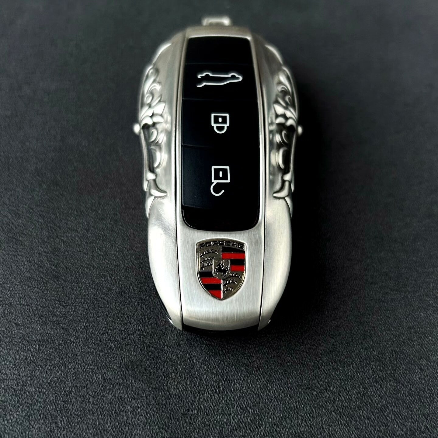 Hand holding precision-crafted Porsche key case, demonstrating substantial weight